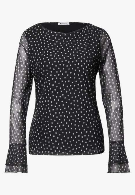 Shirt aus Mesh mit Print und Volantdetails Black Schwarzes Damenoberteil mit transparenten Ärmeln und weißem Punktmuster.