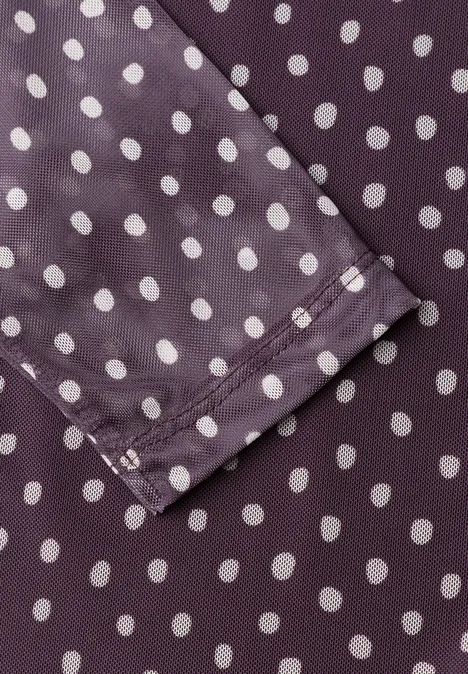 Nahaufnahme eines violetten Stoffes mit weißen Polka-Dots und einer abgenähten Kante einer Manschette.