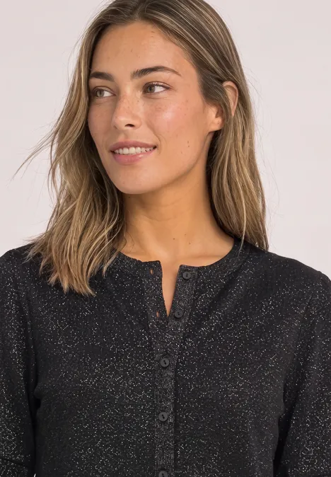 Kurzarm Jacke mit Rundhals und Glitzer Black Eine junge Frau mit mittellangen hellbraunen Haaren und glitzerndem schwarzen Oberteil, schräg zur Seite lächelnd.