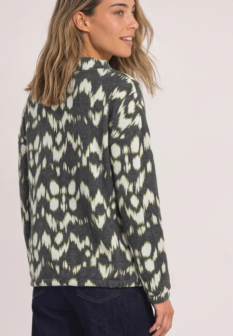 Shirt met lange mouwen, col en print Black Een vrouw draagt een groen-witte trui met ikatpatroon en kijkt over haar schouder.