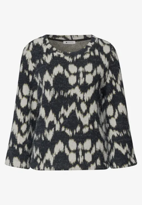 Pull femme noir à motif abstrait blanc, coupe ample et manches longues.