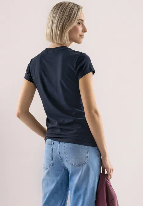 Basic Shirt mit Turtle Neck shadowed navy Junge Frau in schwarzem T-Shirt und hellblauer Jeans, hält eine bordeauxrote Tasche, Ansicht von hinten.