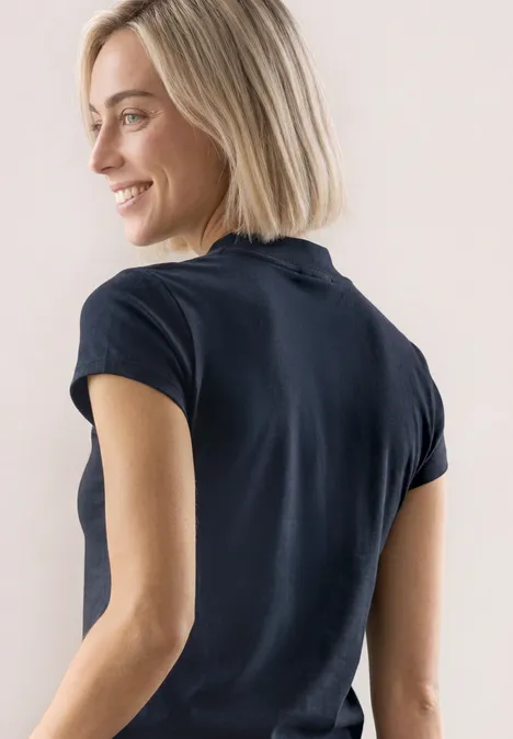 Basic Shirt mit Turtle Neck shadowed navy Lächelnde blonde Frau in schwarzem T-Shirt, seitlich gesehen.