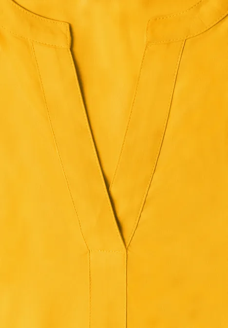Geel shirt met V-hals van zachte stof.