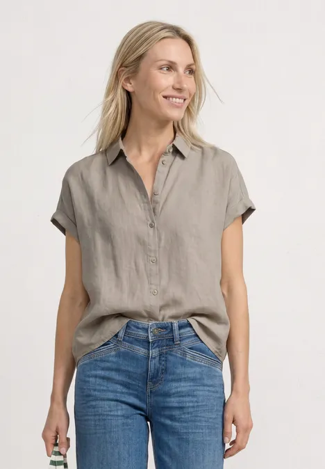 Dropped Shoulder Bluse aus Leinen timeless beige Eine Frau trägt eine kurzärmlige graue Leinenbluse und blaue Jeans.