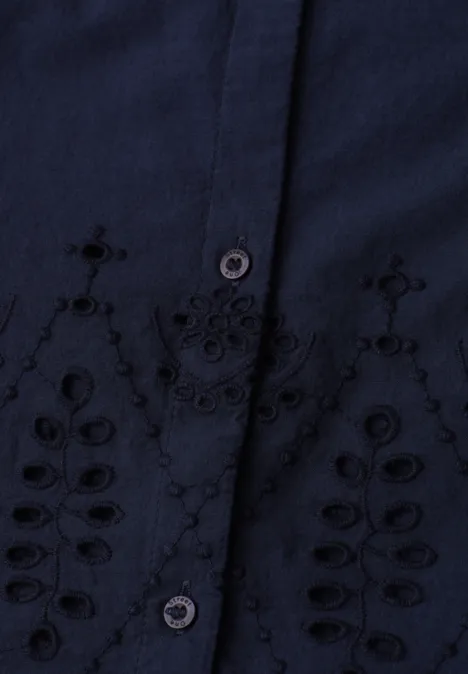Donkerblauw bovenstuk met bloemrijke borduursels rond de knoopsluiting, speels opengewerkt motief.