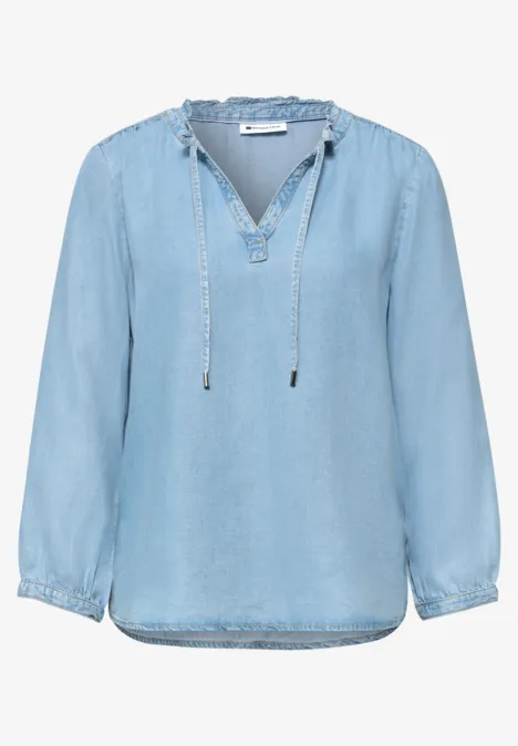 Lichtblauwe denimblouse met V-hals, koordjes en lange mouwen, losse pasvorm.