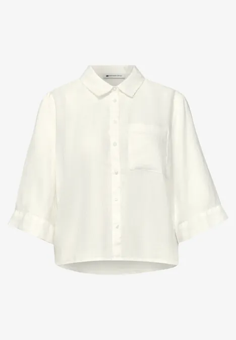 Chemisier blanc ample pour femme, col classique, patte de boutonnage et manches trois-quarts.