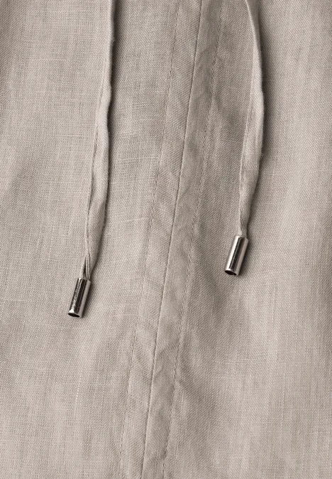 Close-up van beige stof met twee koorden en metalen uiteinden.