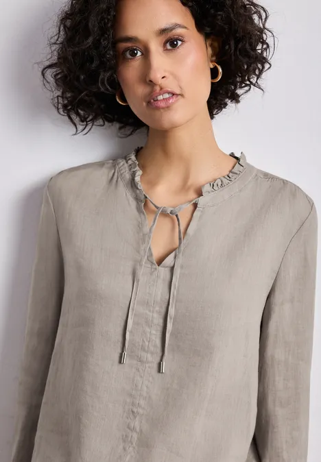 Linnen blouse in lichtgrijs met ruches aan de kraag, striksluiting bij de hals en lange mouwen.