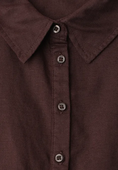 Close-up van een donkerbruin overhemd met kraag en knoopsluiting.