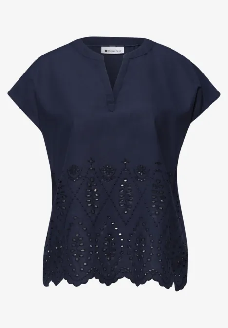 Donkerblauwe damesblouse met korte mouwen, V-hals en decoratieve opengewerkte borduursels onderaan.