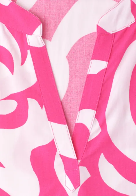 Nahaufnahme eines pink-weißen Oberteils mit abstraktem Muster und V-Ausschnitt.