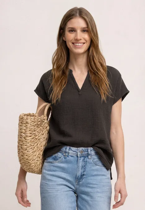 Frau in schwarzem Kurzarmtop und blauen Jeans mit geflochtenem Strohtasche.