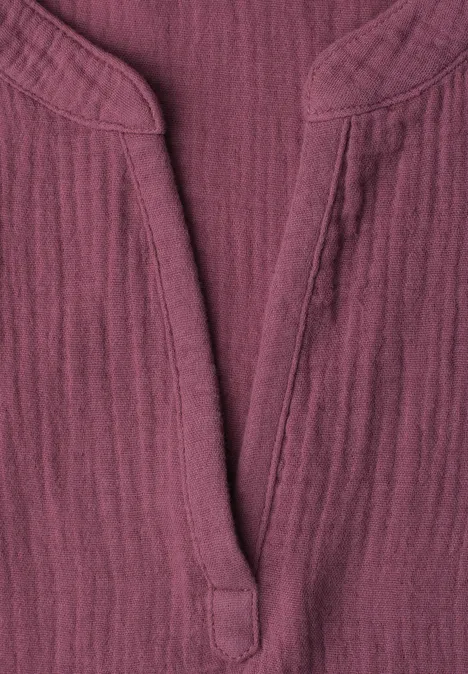 Nahaufnahme eines bordeauxroten, strukturierten Baumwollshirts mit V-Ausschnitt und Stehkragen.