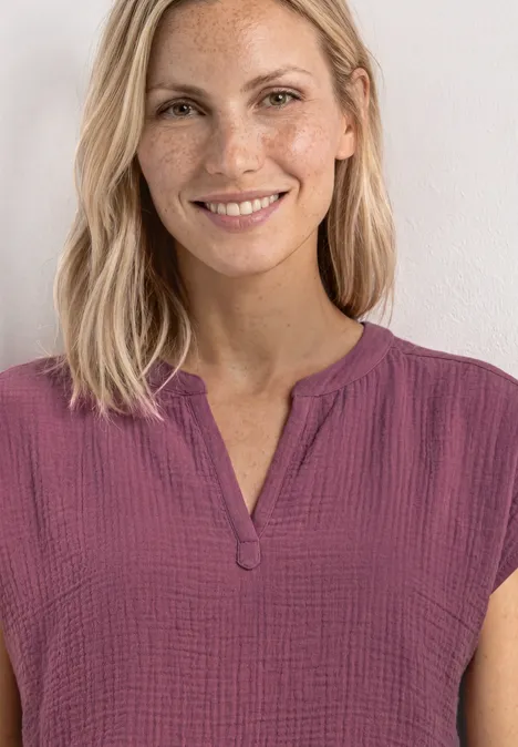 Blusenshirt in Musselin-Qualität dark clouded blush Frau mit blonden Haaren trägt eine kurzärmelige, violett-pinke Bluse mit V-Ausschnitt.