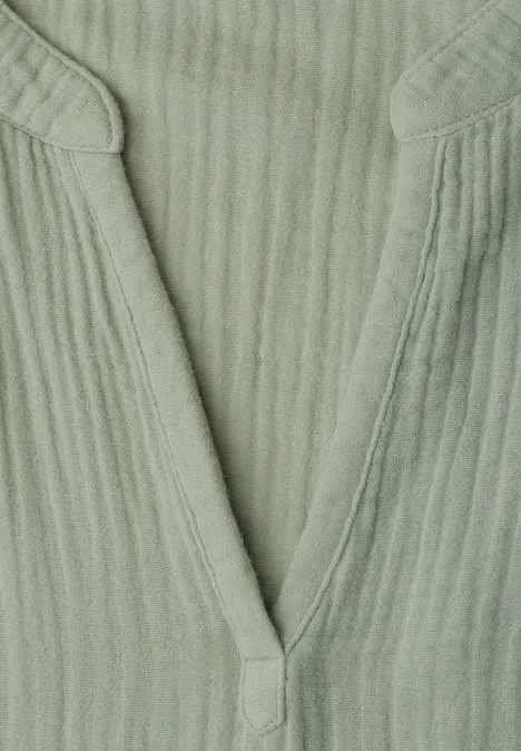 Grünes, geripptes V-Ausschnitt-Oberteil aus weichem Stoff.