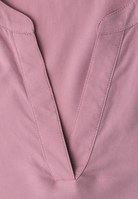 Nahaufnahme eines rosa V-Ausschnitts aus Stoff mit sichtbaren Nähten und feiner Textur.