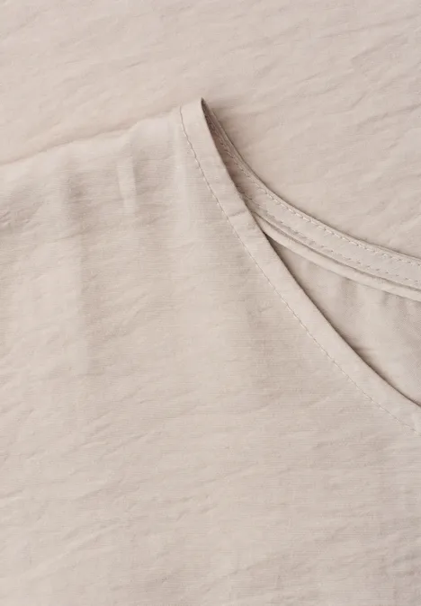 Nahaufnahme eines hellbeigen T-Shirts mit V-Ausschnitt