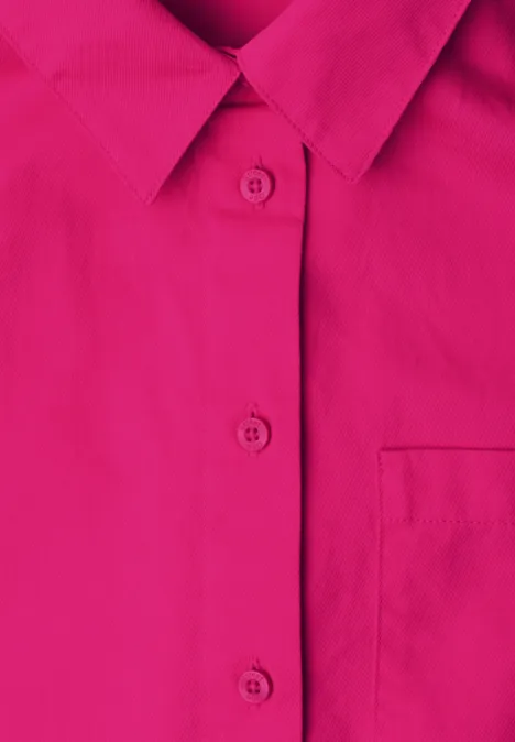Close-up van een felroze overhemd met kraag, knoopsluiting en borstzak.