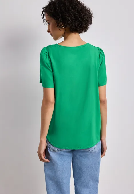 Bluse mit Rundhals und kurzen Puffärmeln ever green Rückenansicht einer Person in grüner Bluse und blauen Jeans.