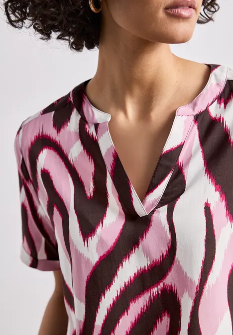 Vrouw draagt top met abstract roze-wit-zwart patroon en V-hals