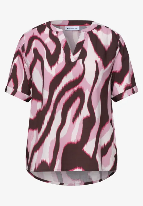 Damesblouse met korte mouwen en abstract zebrapatroon in roze en donkerrood.