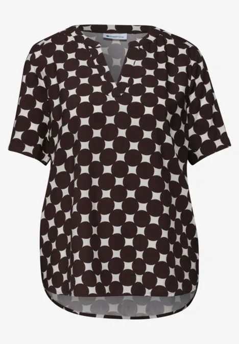 Zwarte blouse met wit cirkelpatroon, V-hals en korte mouwen.