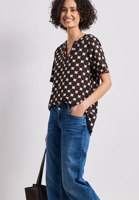 Persoon draagt zwart shirt met witte sterren, een blauwe jeans en een zwarte tas.