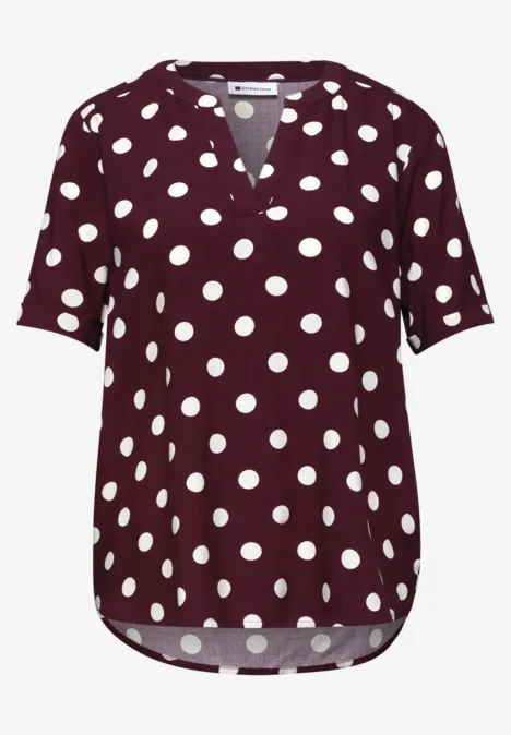 Bordeauxrood polkadotshirt met witte stippen, V-hals en korte mouwen.