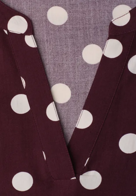 Close-up van een bordeaux V-hals met witte stippen.