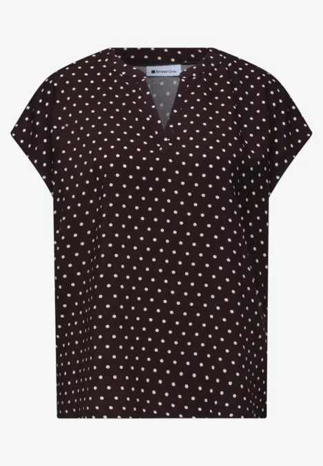 Zwart damesshirt met korte mouwen, V-hals en witte stippen.