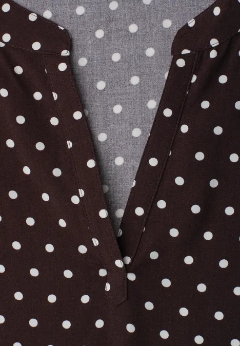 Bruin bovenstuk met witte stippen en een V-hals.