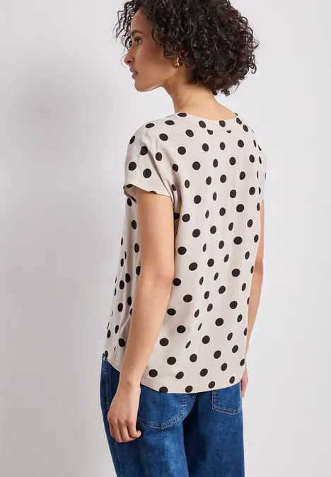 Vrouw van achter gezien met een polkadotshirt en spijkerbroek
