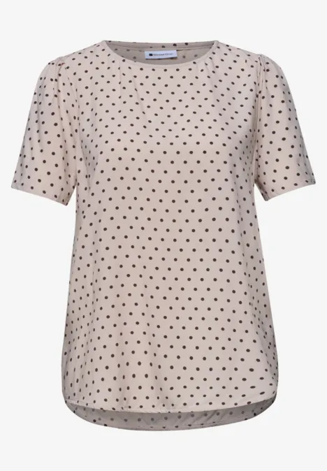 Beiges T-Shirt mit schwarzen Polka-Dots und kurzen Ärmeln.