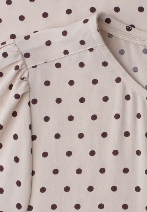 Ein helles Oberteil mit braunen Polka-Dots und Rundhalsausschnitt.