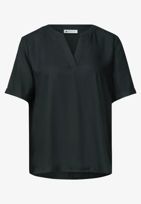 Zwarte, losvallende blouse met V-hals en korte mouwen.