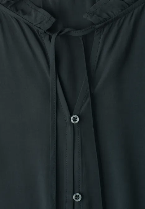 Schwarzes Oberteil mit Knopfleiste und Kordeln am Halsausschnitt.