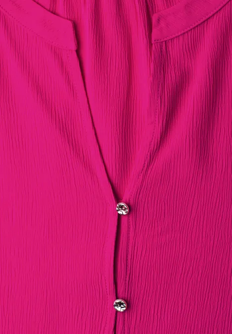 Pinkfarbene Bluse mit feiner Ripp-Struktur und zwei funkelnden Knöpfen in der vorderen Mitte.
