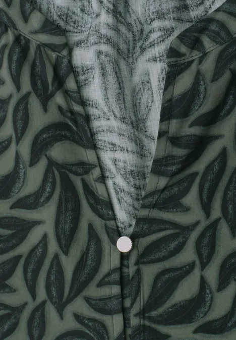 Grünes Blusenhemd mit dunkelgrünem Blattmuster und mittigem Knopf am V-Ausschnitt.