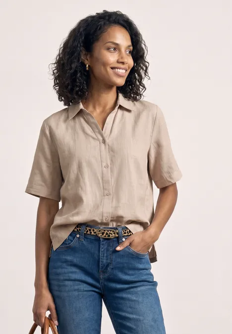 Frau in beiger Kurzarmbluse und blauen Jeans mit Leoprint-Gürtel.