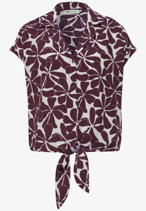 Kurzärmlige, knöpfbare Bluse mit Kragen, violett-weißem Blättermuster und Knoten in der Taille.