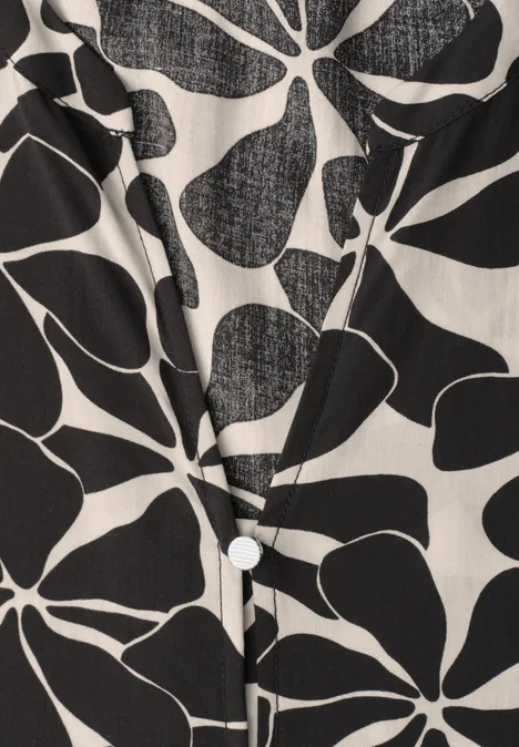 Weißes Hemd mit abstrakten schwarzen Blüten- und Blattmustern und sichtbarem Knopf.