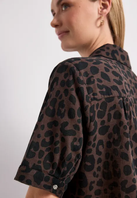 Personne de profil, chemise marron à motif léopard noir, coupe décontractée et manches 3/4.