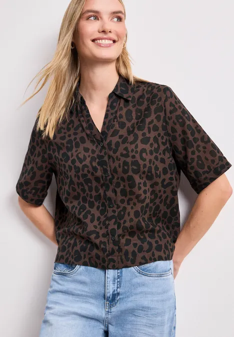 Femme en chemise courte marron à motifs léopard et jean clair.