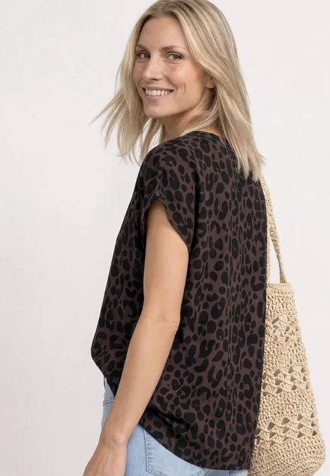 Frau trägt schwarzes Shirt mit Leopardenmuster und eine gehäkelte Tasche.