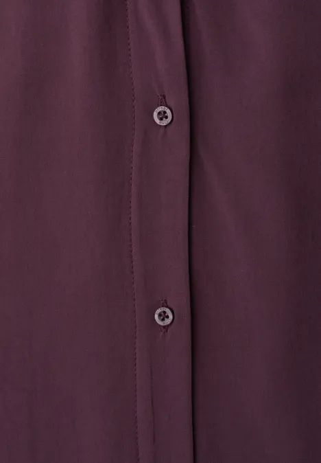 Gros plan d'une chemise bordeaux avec patte de boutonnage et deux boutons