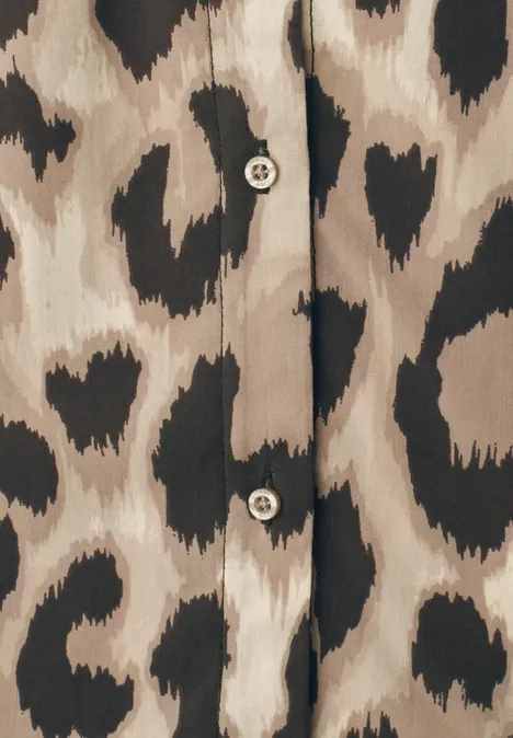 Beige Bluse mit schwarzen, herzförmigen Flecken im Leopardenstil und zwei runden Knöpfen.