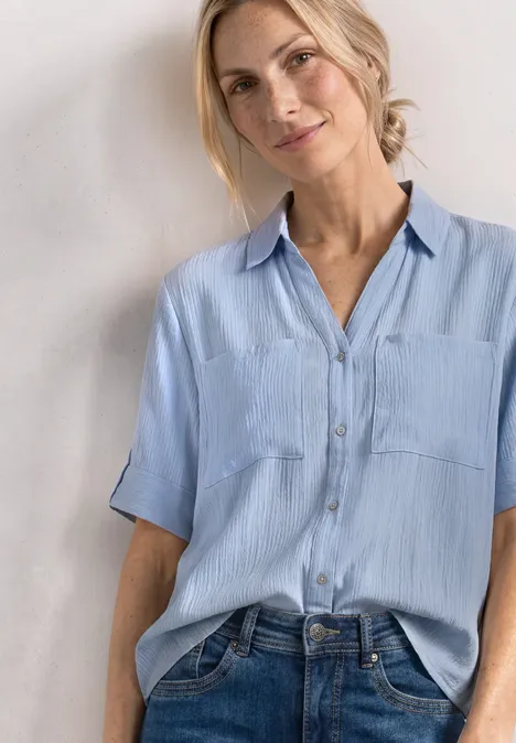 Kurzarm Hemdbluse mit Turn-Up-Details cashmere blue Person trägt hellblaues Kurzarmhemd mit Taschen und Jeans vor schlichter Wand.