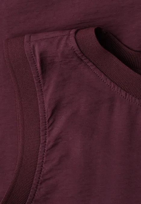 Bild zeigt eine Nahaufnahme eines weinroten ärmellosen Baumwollshirts.